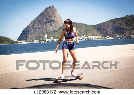 Young woman skateboarding on pavement View Large Photo Image Stock Image - Young woman skateboarding on pavement. Fotosearch