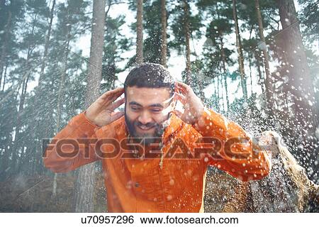 Stock Photograph - Young woman sprinkling boyfriend with water in forest. Fotosearch