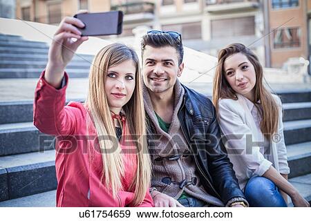 "Young woman taking smartphone selfie with friends on stairway, Cagliari, Sardinia, Italy" View Large Photo Image Stock Photo - "Young woman taking smartphone selfie with friends on stairway, Cagliari, Sardinia, Italy". Fotosearch