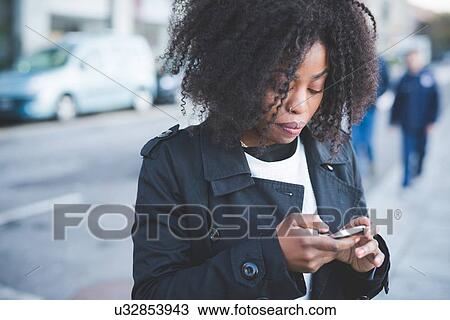 Stock Image - "Young woman texting on smartphone, Lake Como, Como, Italy". Fotosearch
