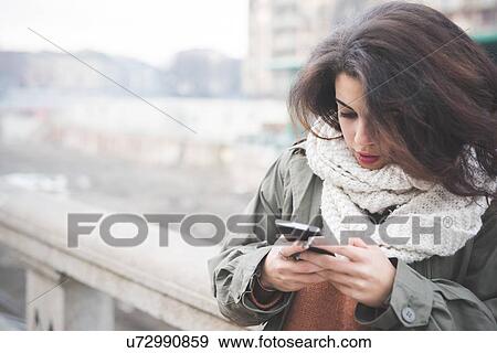 Stock Photo - Young woman texting on smartphone. Fotosearch