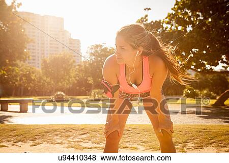 Young woman training listening to earphones in park View Large Photo Image Stock Photo - Young woman training listening to earphones in park. Fotosearch