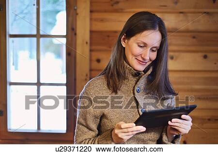 "Young woman using digital tablet in log cabin, Posio, Lapland, Finland" View Large Photo Image Stock Image - "Young woman using digital tablet in log cabin, Posio, Lapland, Finland". Fotosearch