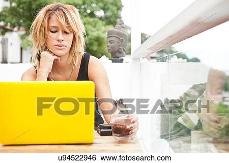 Stock Photograph - "Young woman using laptop on rooftop terrace, Rio De Janeiro, Brazil". Fotosearch