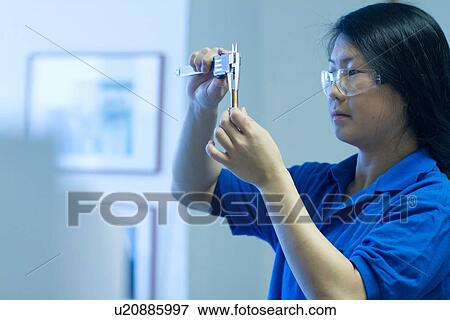 Stock Photo - Young woman using specialist measuring device. Fotosearch