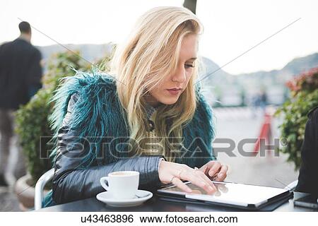 "Young woman using touchscreen on digital tablet at sidewalk cafe, Lake Como, Como, Italy" View Large Photo Image Stock Photograph - "Young woman using touchscreen on digital tablet at sidewalk cafe, Lake Como, Como, Italy". Fotosearch