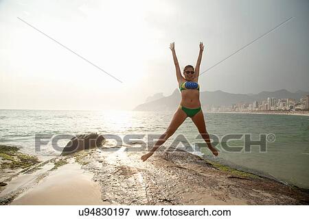 "Young woman wearing bikini jumping mid air on Ipanema beach, Rio De Janeiro, Brazil" View Large Photo Image Stock Photo - "Young woman wearing bikini jumping mid air on Ipanema beach, Rio De Janeiro, Brazil". Fotosearch