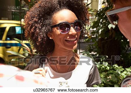 Stock Photo - "Young woman wearing sunglasses, smiling". Fotosearch