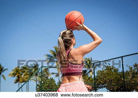 "Young woman with basketball, about to take a shot, rear view" View Large Photo Image Stock Photo - "Young woman with basketball, about to take a shot, rear view". Fotosearch