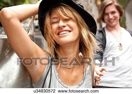 Young woman with boyfriend on street holding onto her hat View Large Photo Image Stock Image - Young woman with boyfriend on street holding onto her hat. Fotosearch