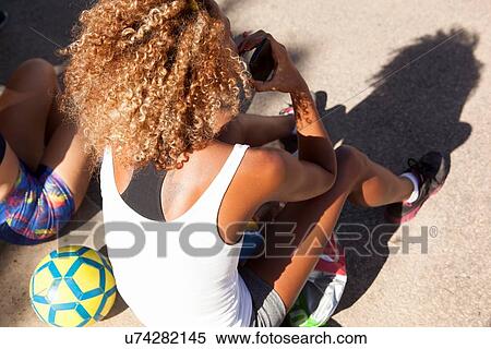 Stock Photography - "Young woman with curly hair sitting on floor, high angle". Fotosearch