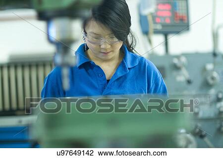 Stock Image - Young woman working in industrial workshop. Fotosearch