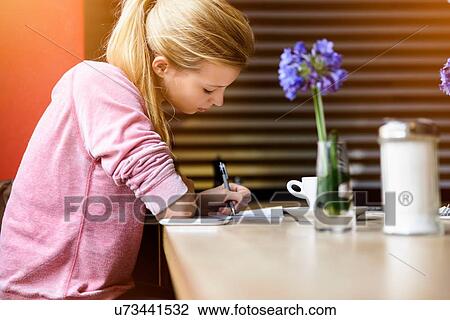 Young woman writing notes at cafe table View Large Photo Image Stock Image - Young woman writing notes at cafe table. Fotosearch