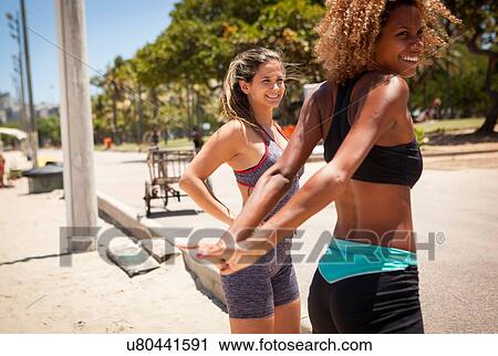 Stock Image - Young women stretching on beach. Fotosearch