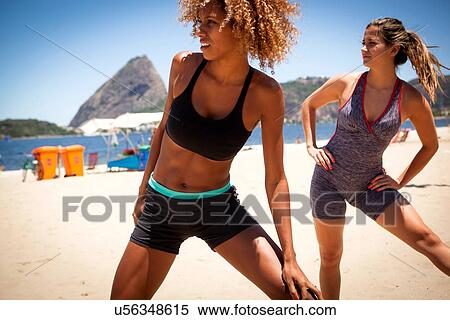 Stock Photography - Young women stretching on beach. Fotosearch