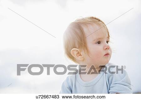 Stock Image - Baby girl (6-11 months) looking away. Fotosearch