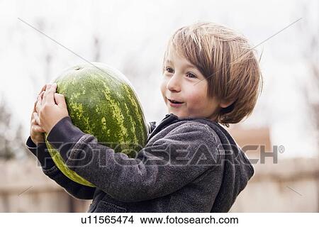 Picture - Boy (6-7) carrying watermelon. Fotosearch