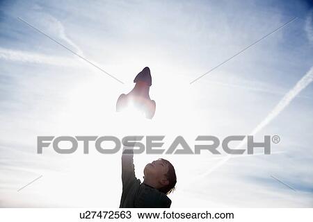 Stock Image - Boy (6-7) playing with toy rocket. Fotosearch