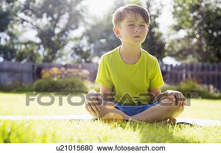 Stock Image - Boy (6-7) sitting in grass. Fotosearch