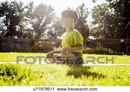 Boy (6-7) sitting in grass View Large Photo Image Stock Image - Boy (6-7) sitting in grass. Fotosearch