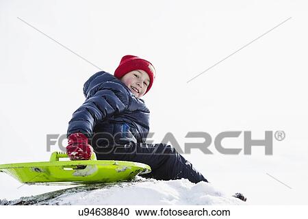Stock Image - Boy (6-7) sledding in winter. Fotosearch