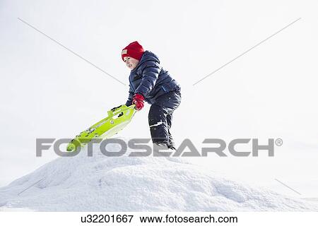 Stock Photo - Boy (6-7) sledding in winter. Fotosearch