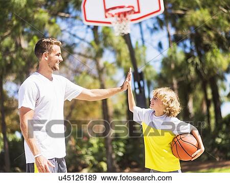 Stock Photo - Boy (8-9) high fiving his brother. Fotosearch