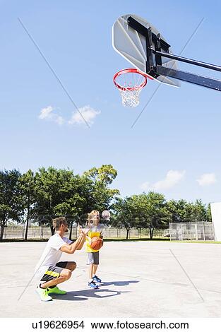 Picture - Boy (8-9) playing basketball with his brother. Fotosearch