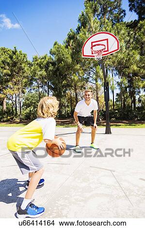 Boy (8-9) playing basketball with his brother View Large Photo Image Picture - Boy (8-9) playing basketball with his brother. Fotosearch