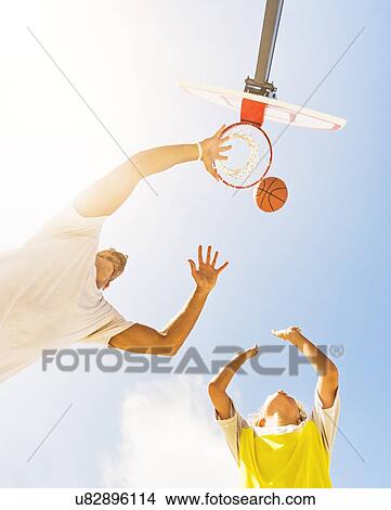 Boy (8-9) playing basketball with his brother View Large Photo Image Picture - Boy (8-9) playing basketball with his brother. Fotosearch