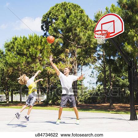 Stock Image - Boy (8-9) playing basketball with his brother. Fotosearch