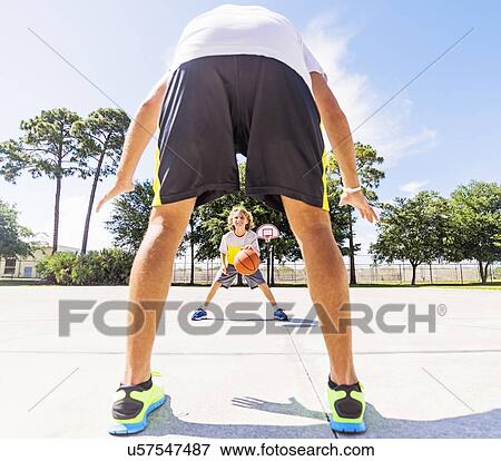 Stock Photo - Boy (8-9) playing basketball with his brother. Fotosearch