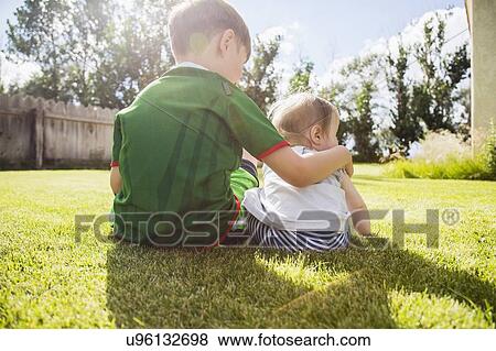 Brother (6-7) and sister (6-11months) sitting in grass View Large Photo Image Stock Photo - Brother (6-7) and sister (6-11months) sitting in grass. Fotosearch