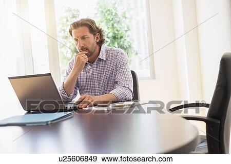 Businessman using laptop at table View Large Photo Image Stock Photo - Businessman using laptop at table. Fotosearch