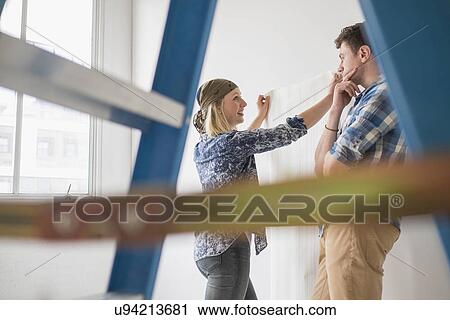 Stock Image - Couple choosing wallpaper for house. Fotosearch