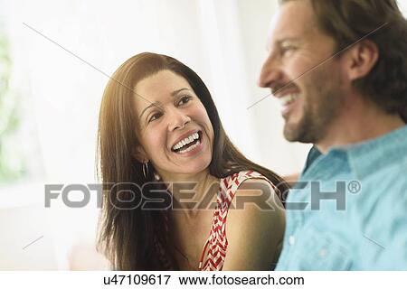 Couple laughing on sofa View Large Photo Image Stock Photo - Couple laughing on sofa. Fotosearch