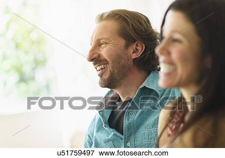 Couple laughing on sofa View Large Photo Image Stock Photo - Couple laughing on sofa. Fotosearch