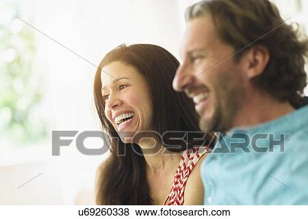 Stock Photo - Couple laughing on sofa. Fotosearch