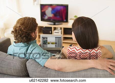 Stock Image - Couple using laptop on sofa. Fotosearch