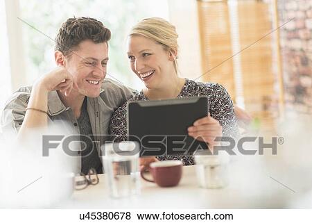 Stock Photo - Couple using tablet pc in cafe. Fotosearch