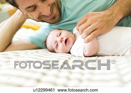 Father with baby boy (6-11 months) on bed View Large Photo Image Stock Image - Father with baby boy (6-11 months) on bed. Fotosearch