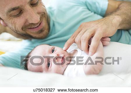 Father with baby boy (6-11 months) on bed View Large Photo Image Stock Photo - Father with baby boy (6-11 months) on bed. Fotosearch