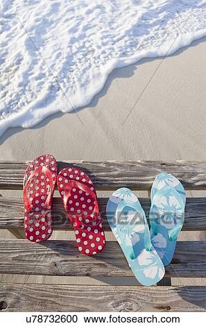 Stock Image - Flip flops on pier by sea. Fotosearch