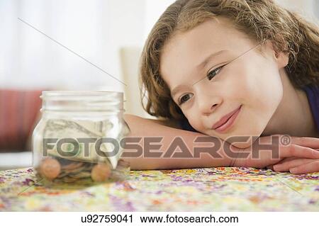 Girl (10-11) girl looking at jar full of money View Large Photo Image Stock Image - Girl (10-11) girl looking at jar full of money. Fotosearch