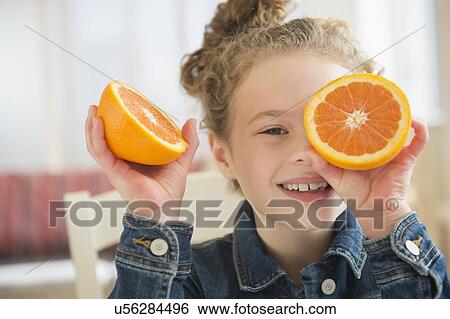 Stock Photograph - Girl (10-11) holding orange. Fotosearch