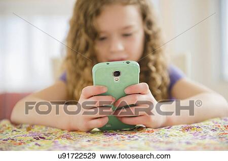Girl (10-11) playing with smart phone View Large Photo Image Stock Photo - Girl (10-11) playing with smart phone. Fotosearch