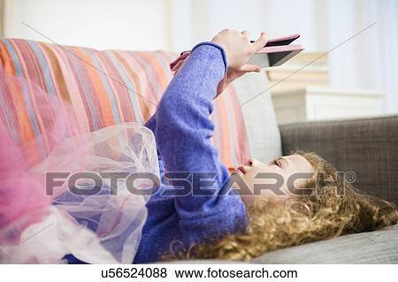 Stock Photo - Girl (10-11) wearing tutu holding digital tablet. Fotosearch