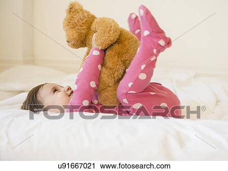 Girl (2-3) lying on bed with teddy bear View Large Photo Image Stock Image - Girl (2-3) lying on bed with teddy bear. Fotosearch