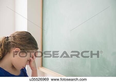 Stock Photo - Girl doing face palm in front of green blackboard. Fotosearch