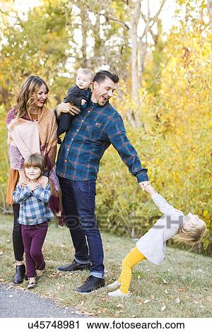 Stock Image - "Happy family with tree children (6-11 months, 2-3, 4-5) in park". Fotosearch